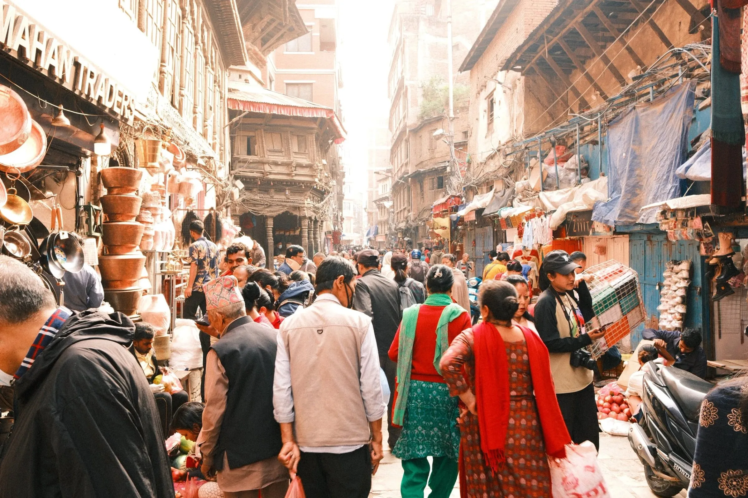 A crowded street in Ason Bazaar lined with shops and hanging goods