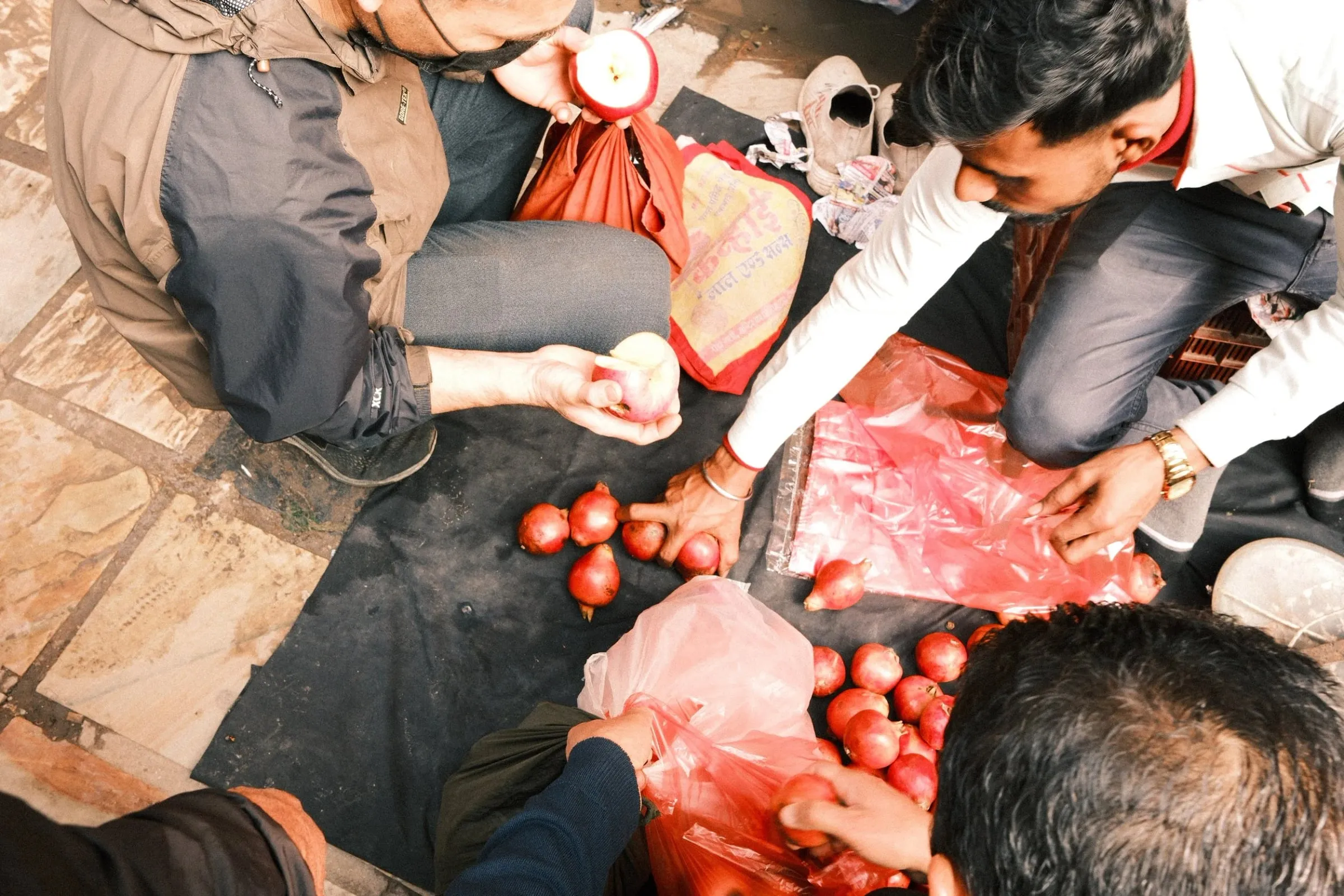 Hands reaching over a pile of pomegranates at a street stall