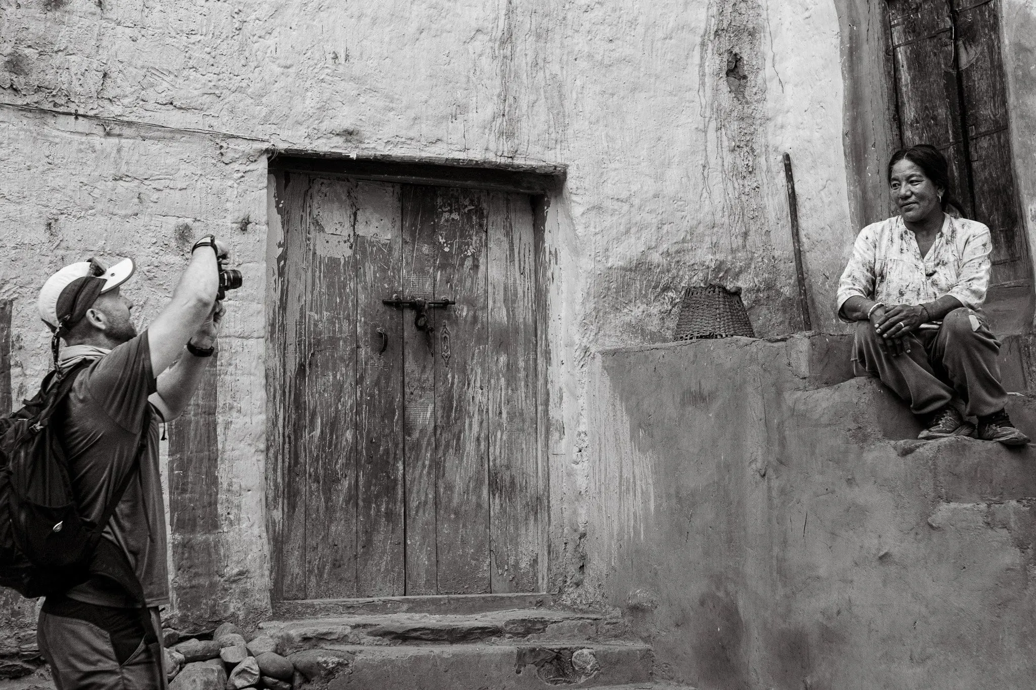 Black and white photograph of a man photographing a local woman in Upper Mustang, Nepal.