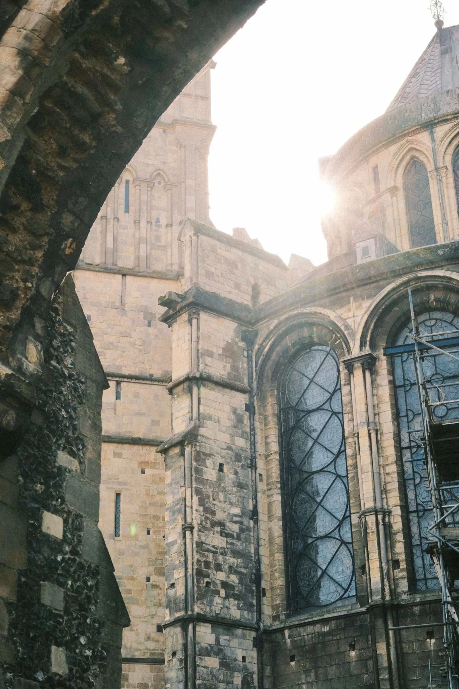 Canterbury Cathedral seen through a stone archway with the sun behind it