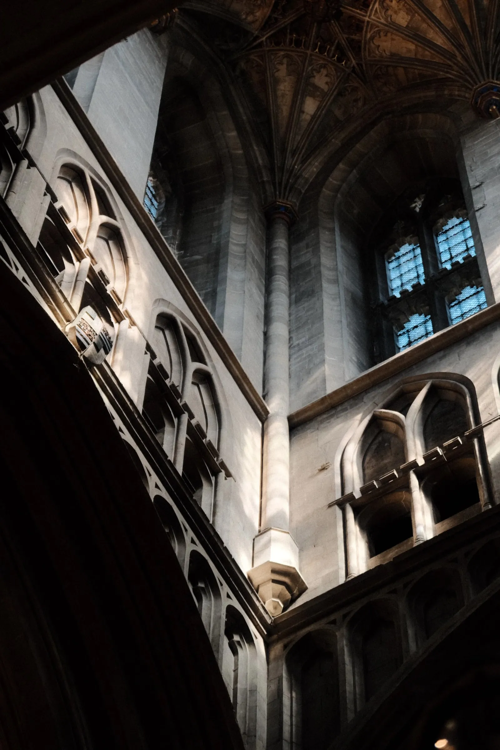 Looking up at stone arcades and windows towards the vaulted ceiling inside Canterbury Cathedral