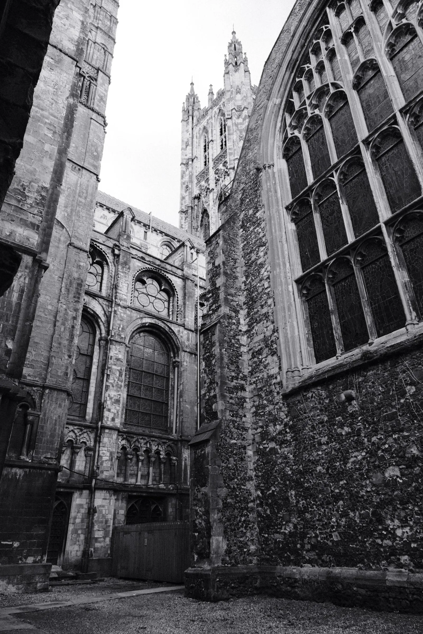 Black and white photo of cathedral walls and the central tower seen from a narrow courtyard