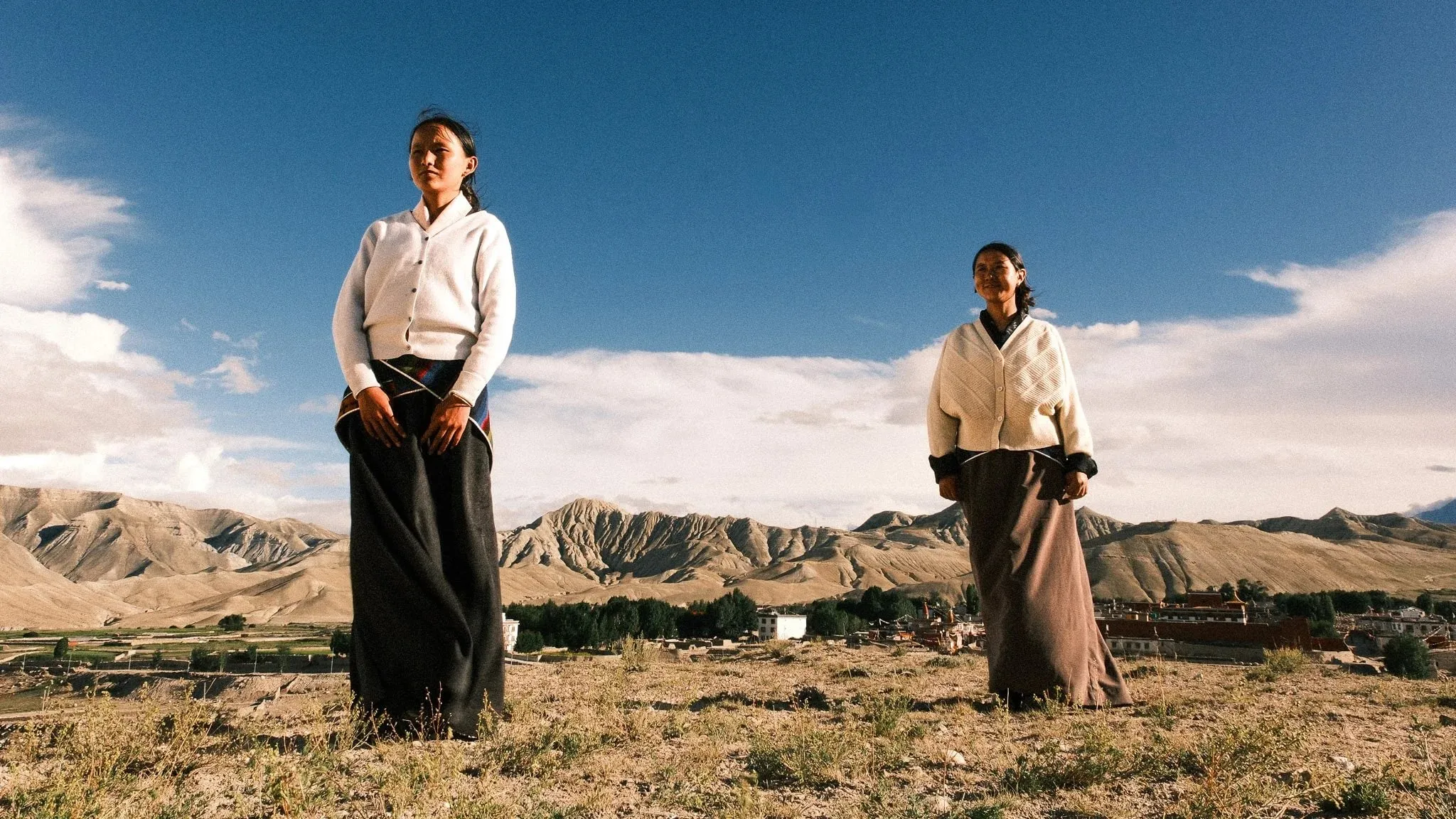 Two women in traditional dress standing on open grassland near Choser