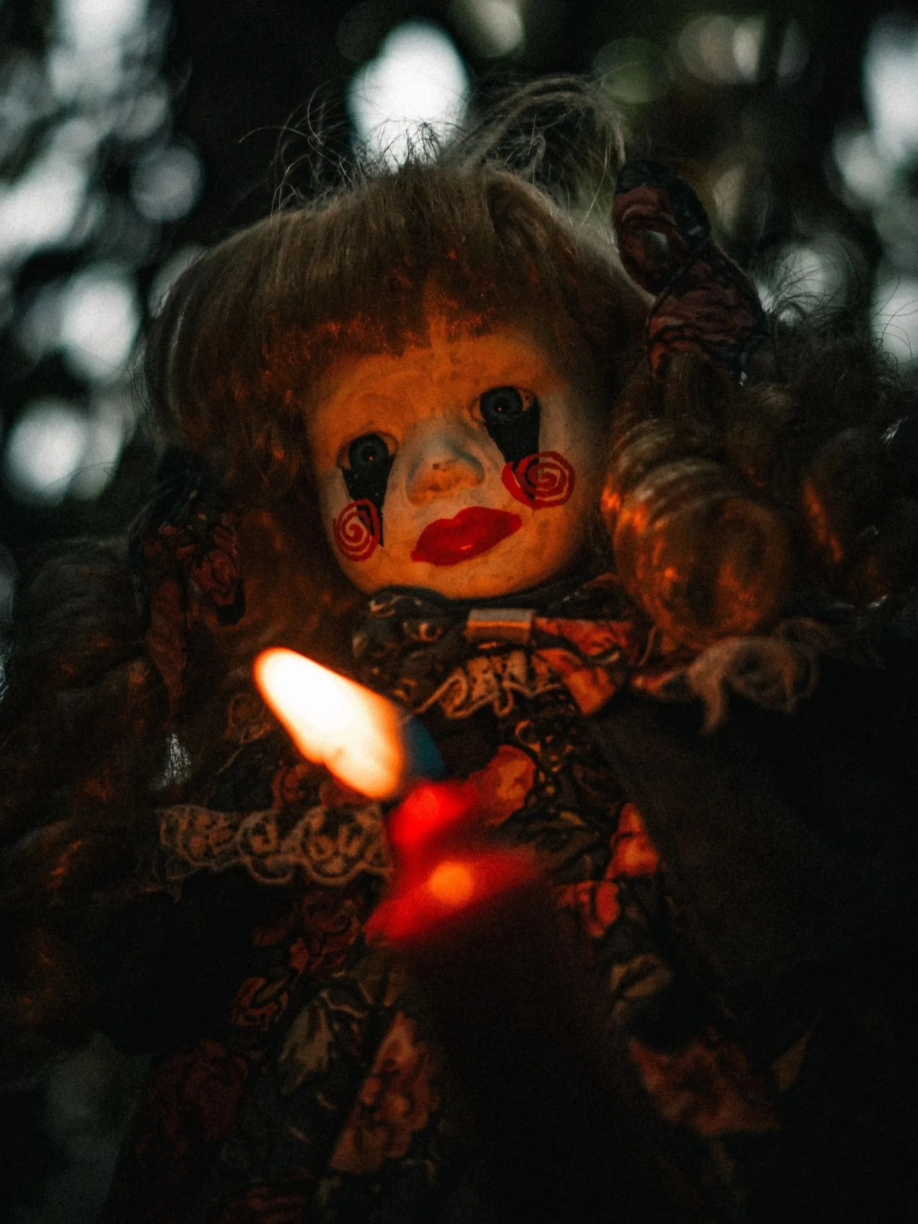 A painted doll with a candle in low light