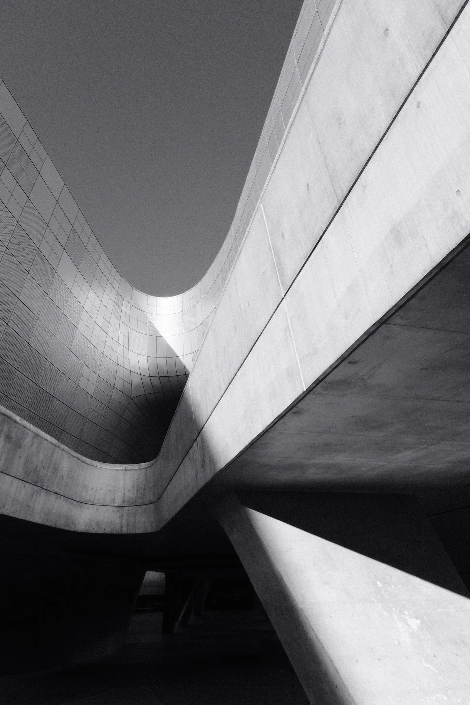 Black and white view up through the curving concrete of Dongdaemun Design Plaza