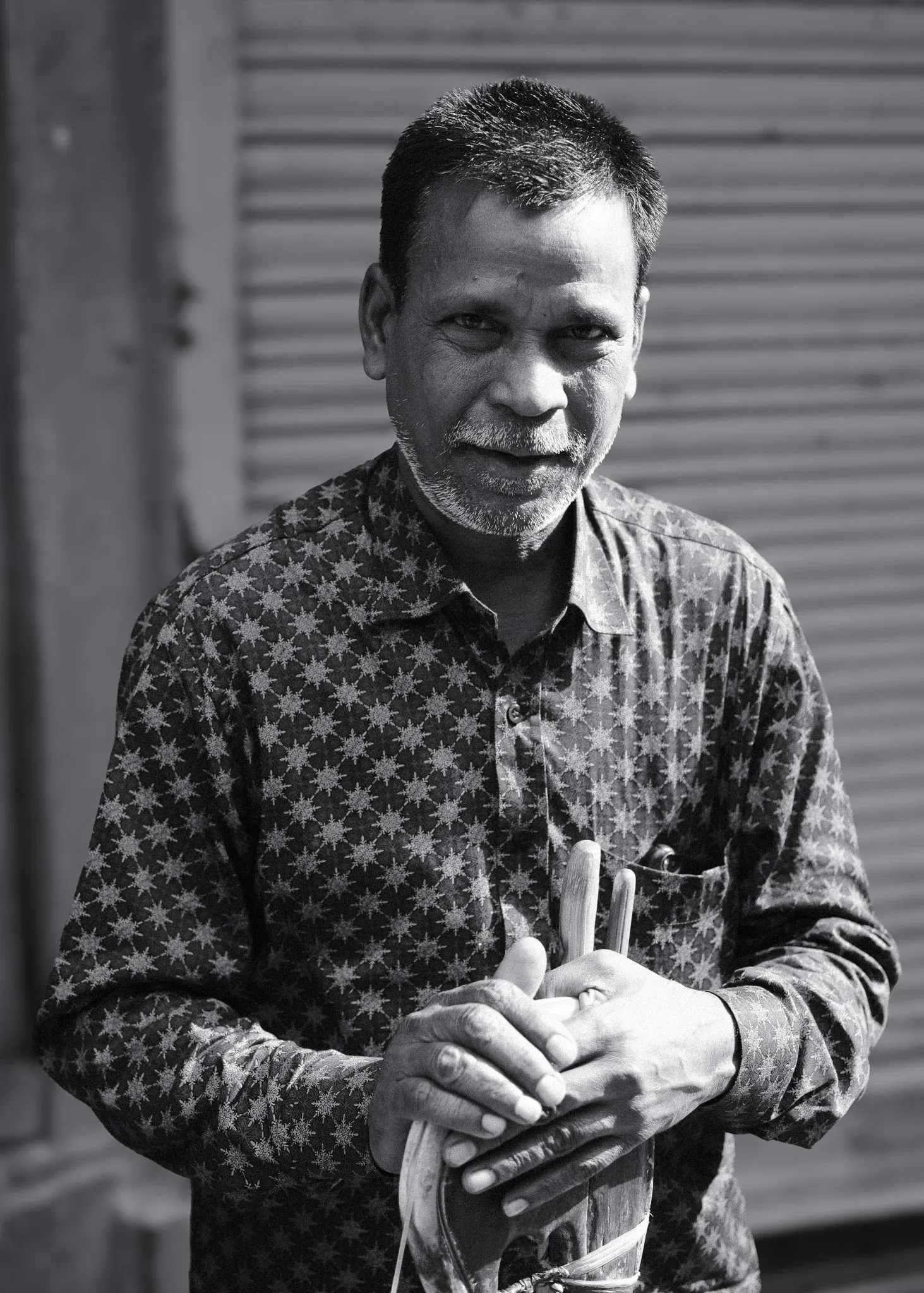Black and white portrait of a man in a patterned shirt, looking at the camera