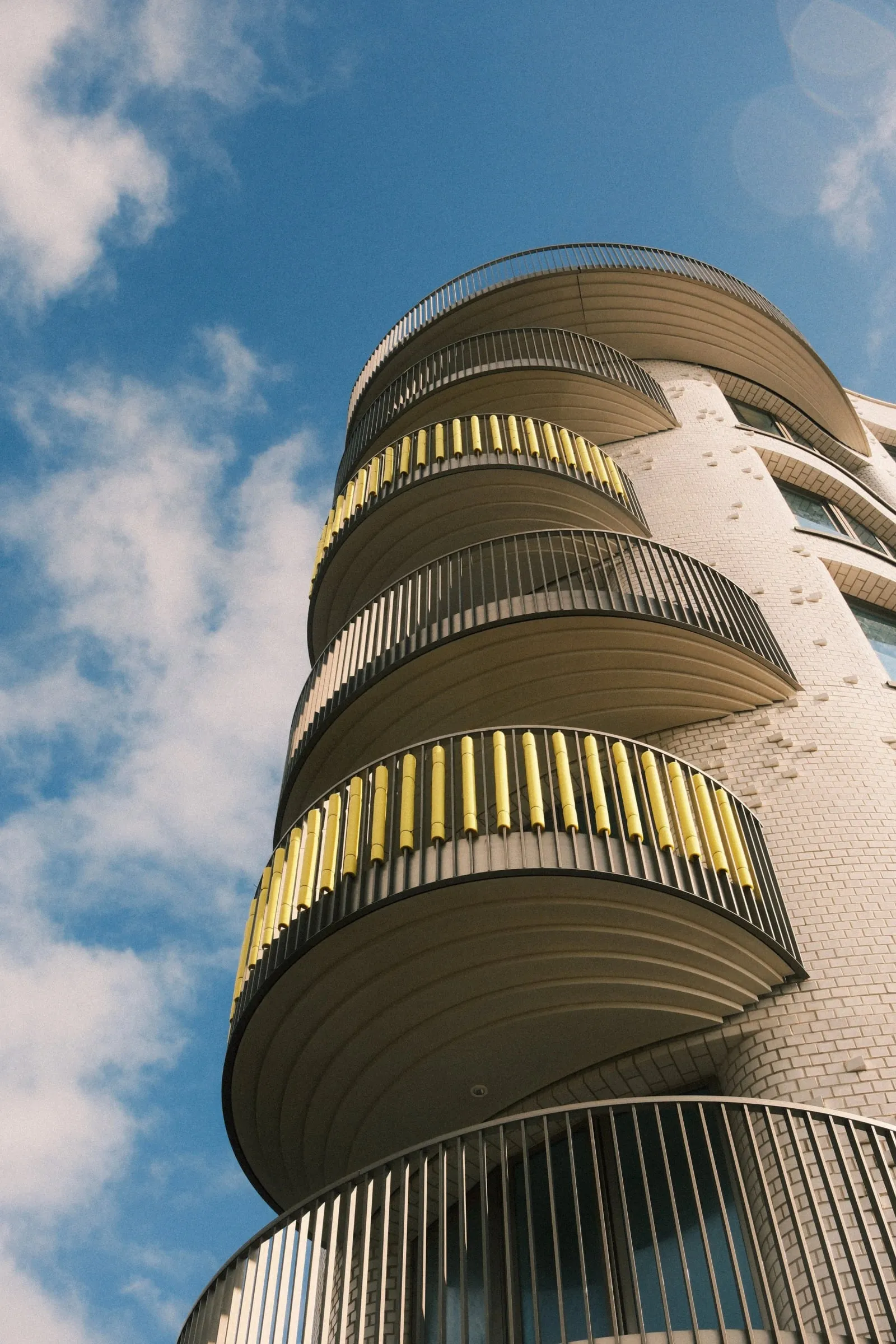 Looking up at the curved balconies of a seafront apartment block against a blue sky