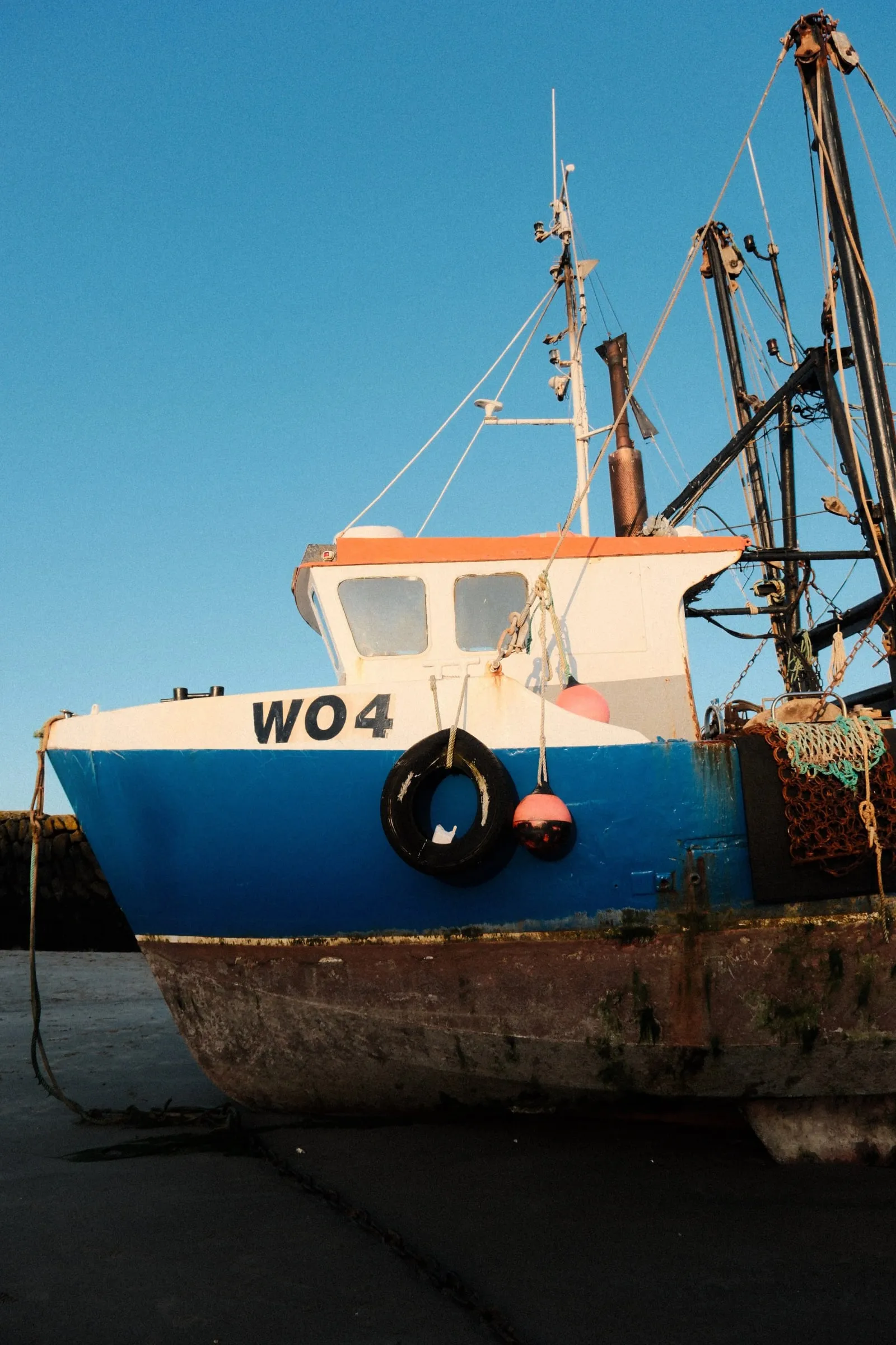 A blue and white fishing boat on the hard at Folkestone harbour