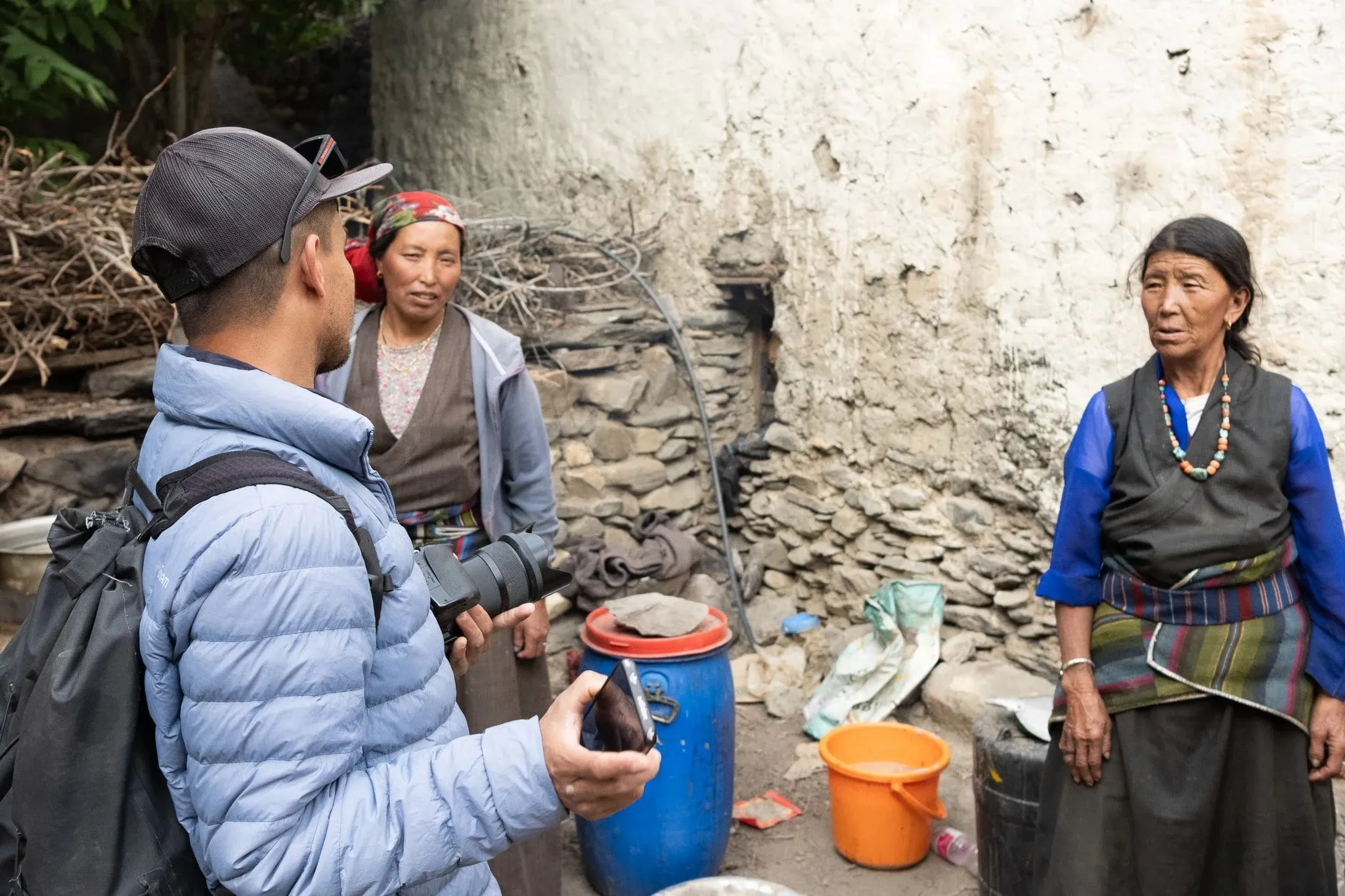A guide talking with two women in a village courtyard
