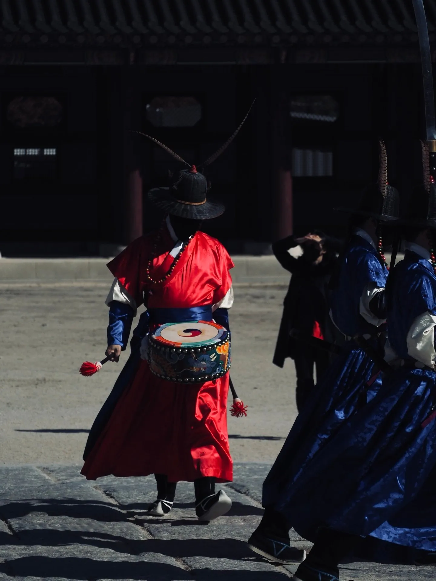 A guard in a red uniform carries a drum during the changing of the guard at Gyeongbokgung