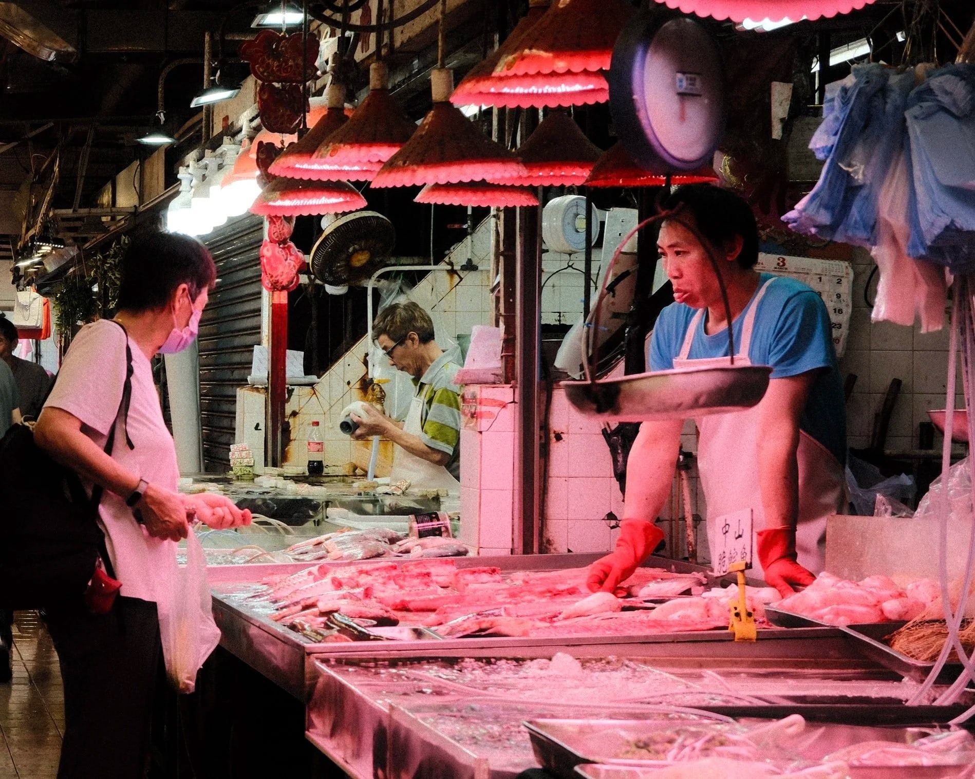 Stallholders working at a market stall under red lamps