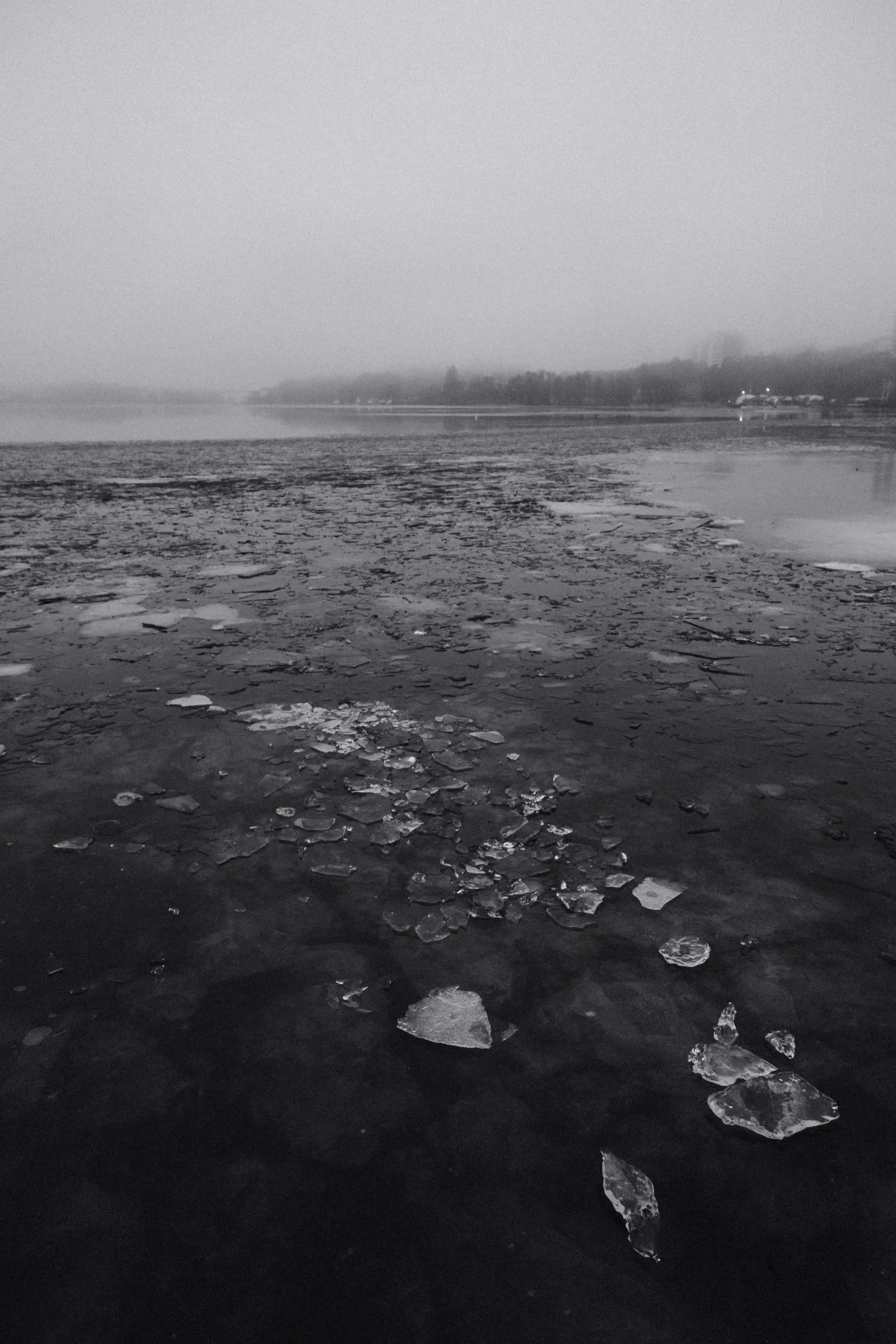Black and white photo of broken ice floating on misty water