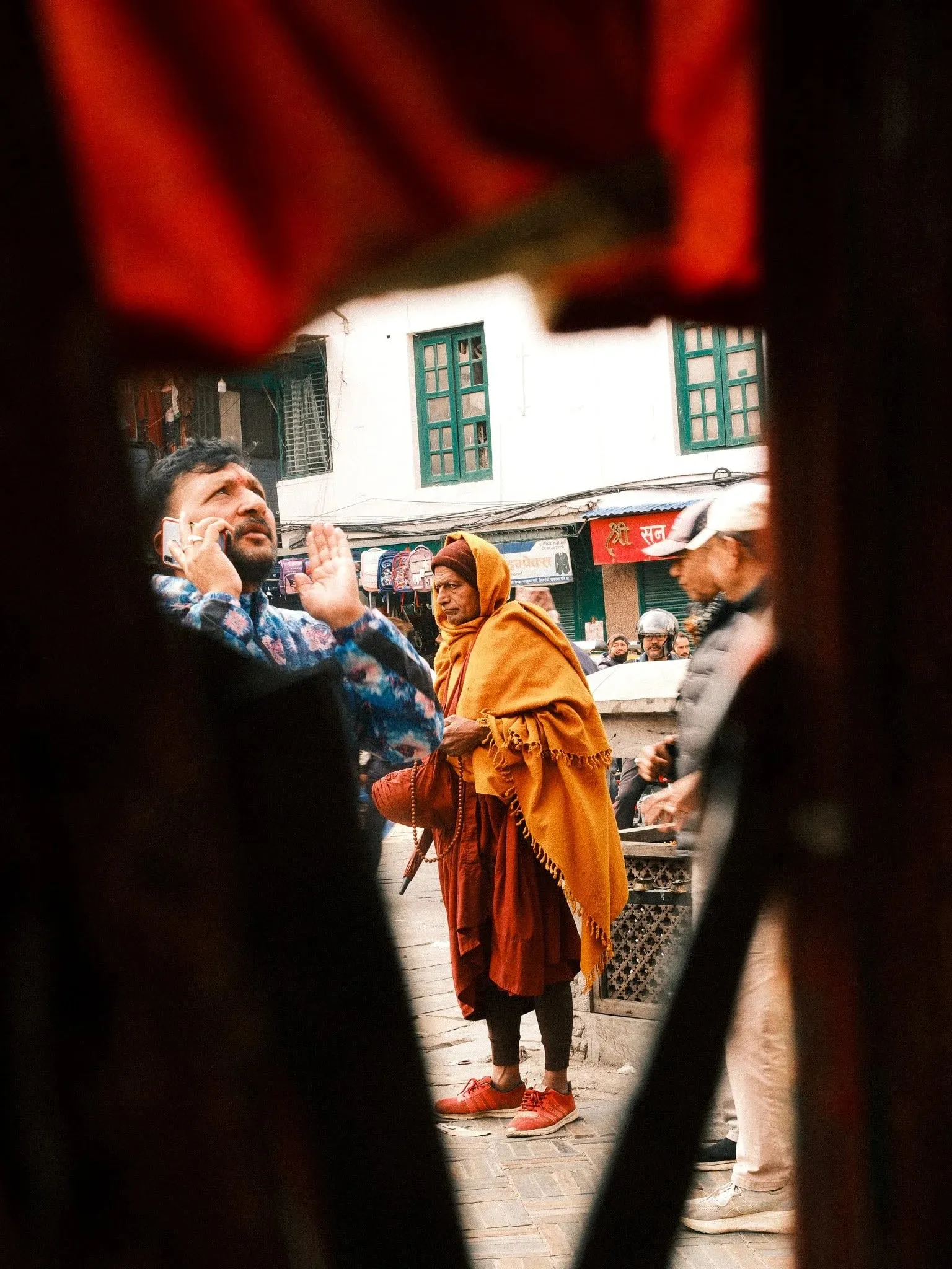 People on a street seen through a gap in red curtains