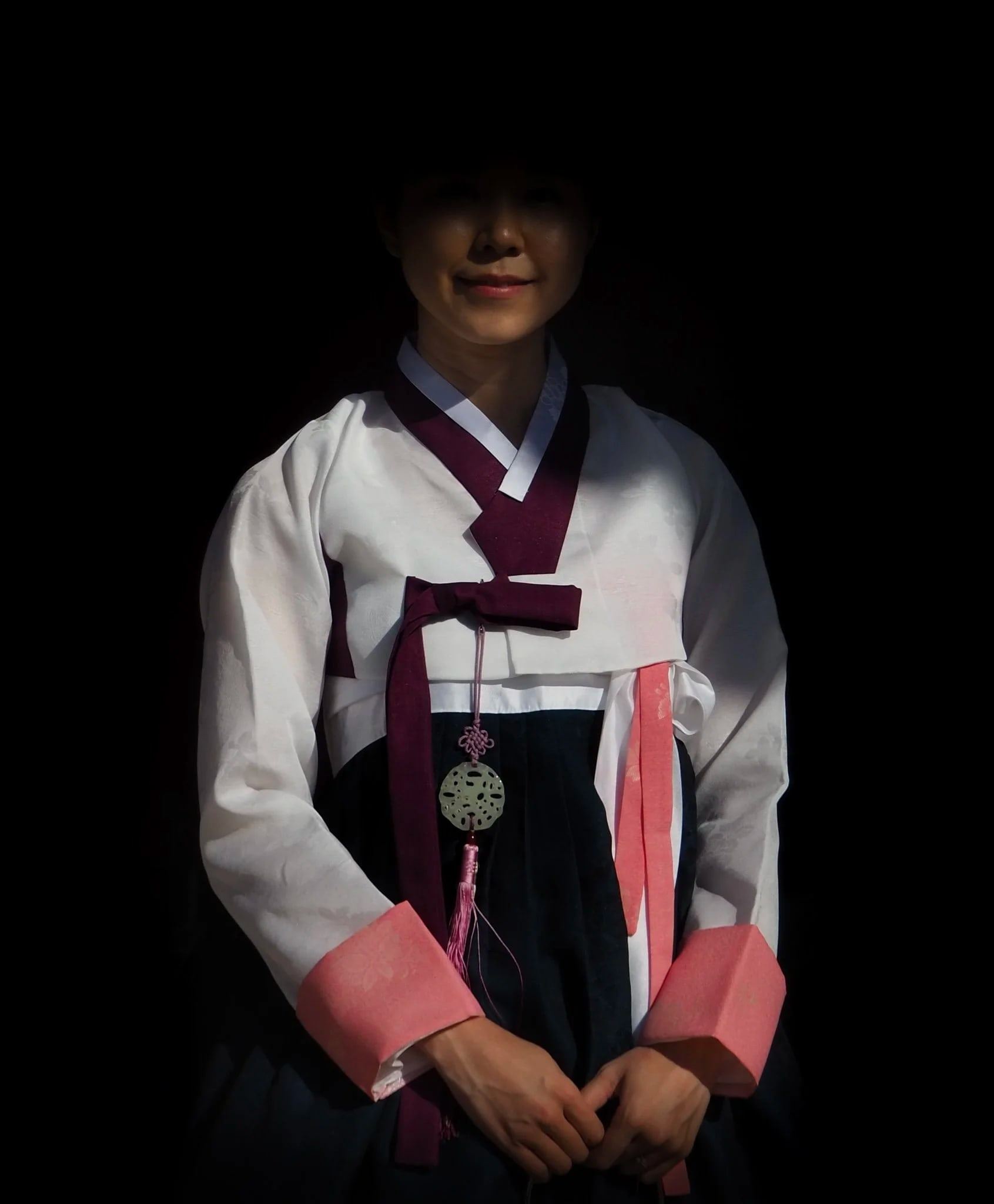 Woman in a white and navy hanbok emerging from shadow