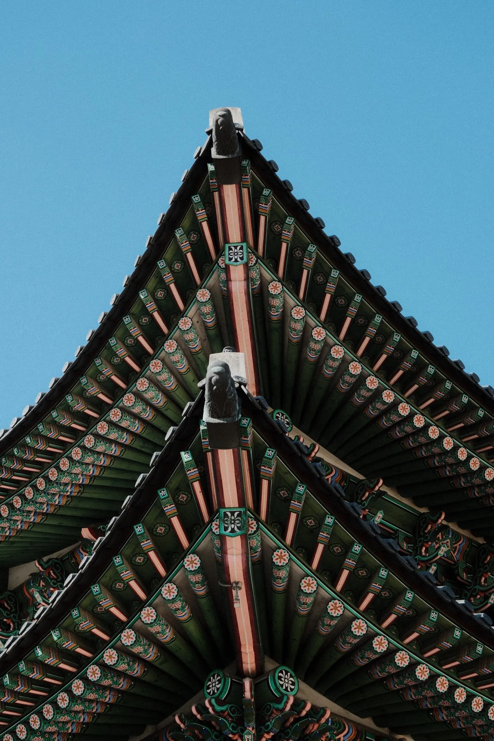 Painted eaves of a palace roof at Gyeongbokgung against a blue sky