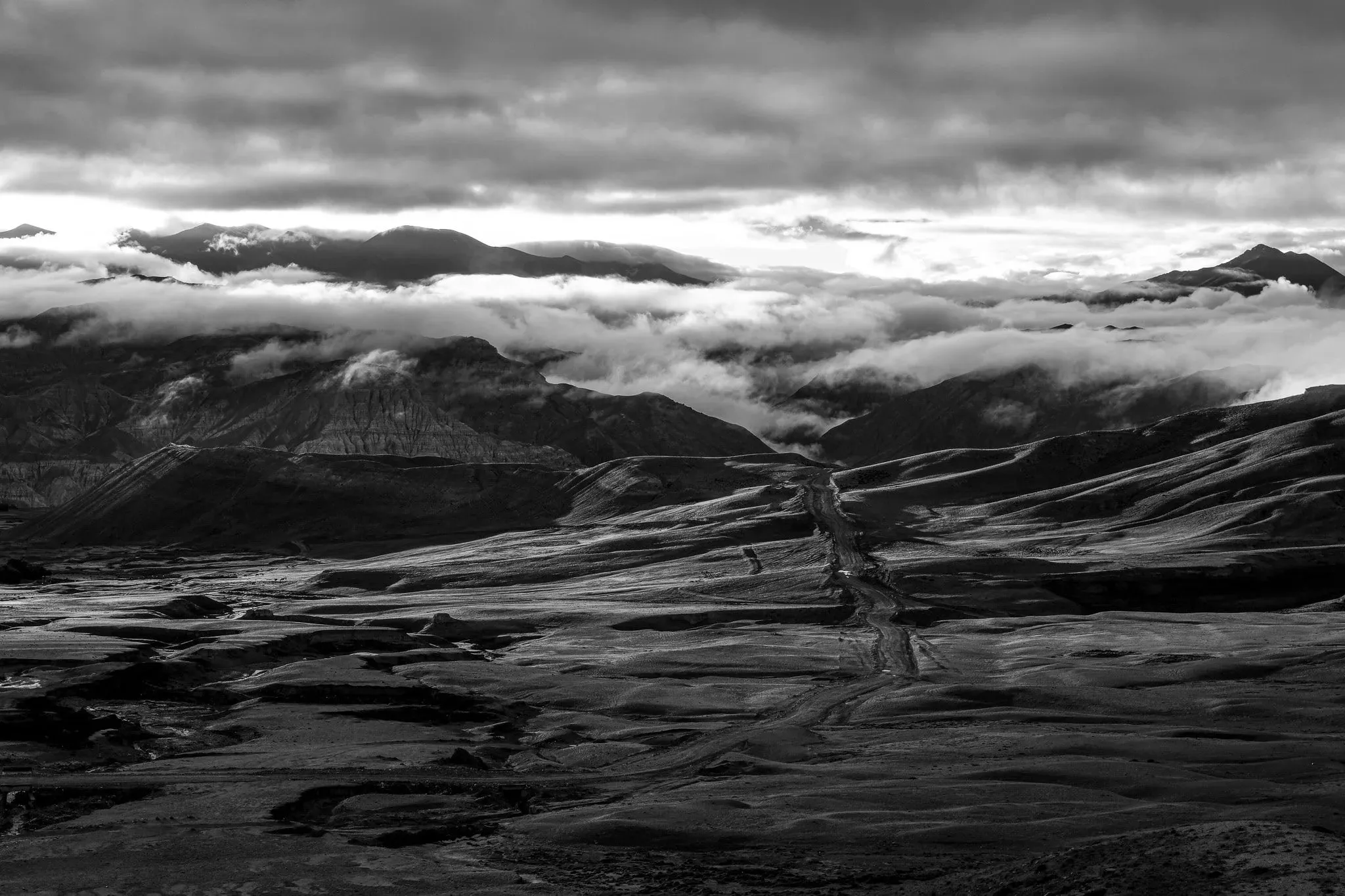 Black and white photo of a wide valley under heavy cloud near Lo Manthang