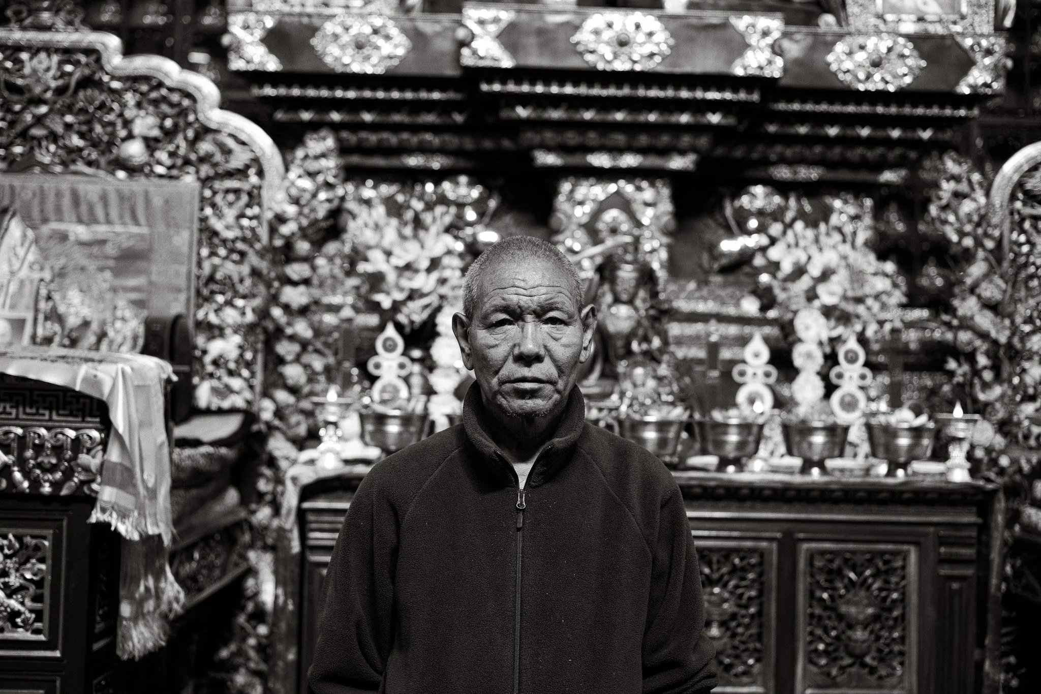 Black and white portrait of a man standing in front of an ornate shrine at Lubra