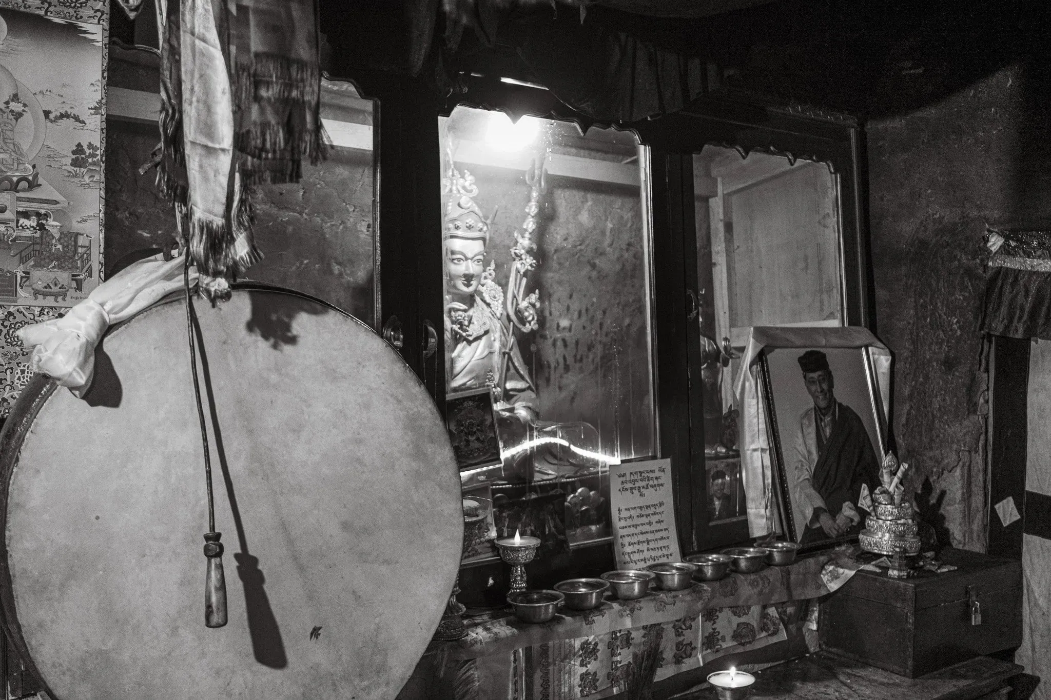 Black and white photo of a large drum and offerings inside a monastery shrine
