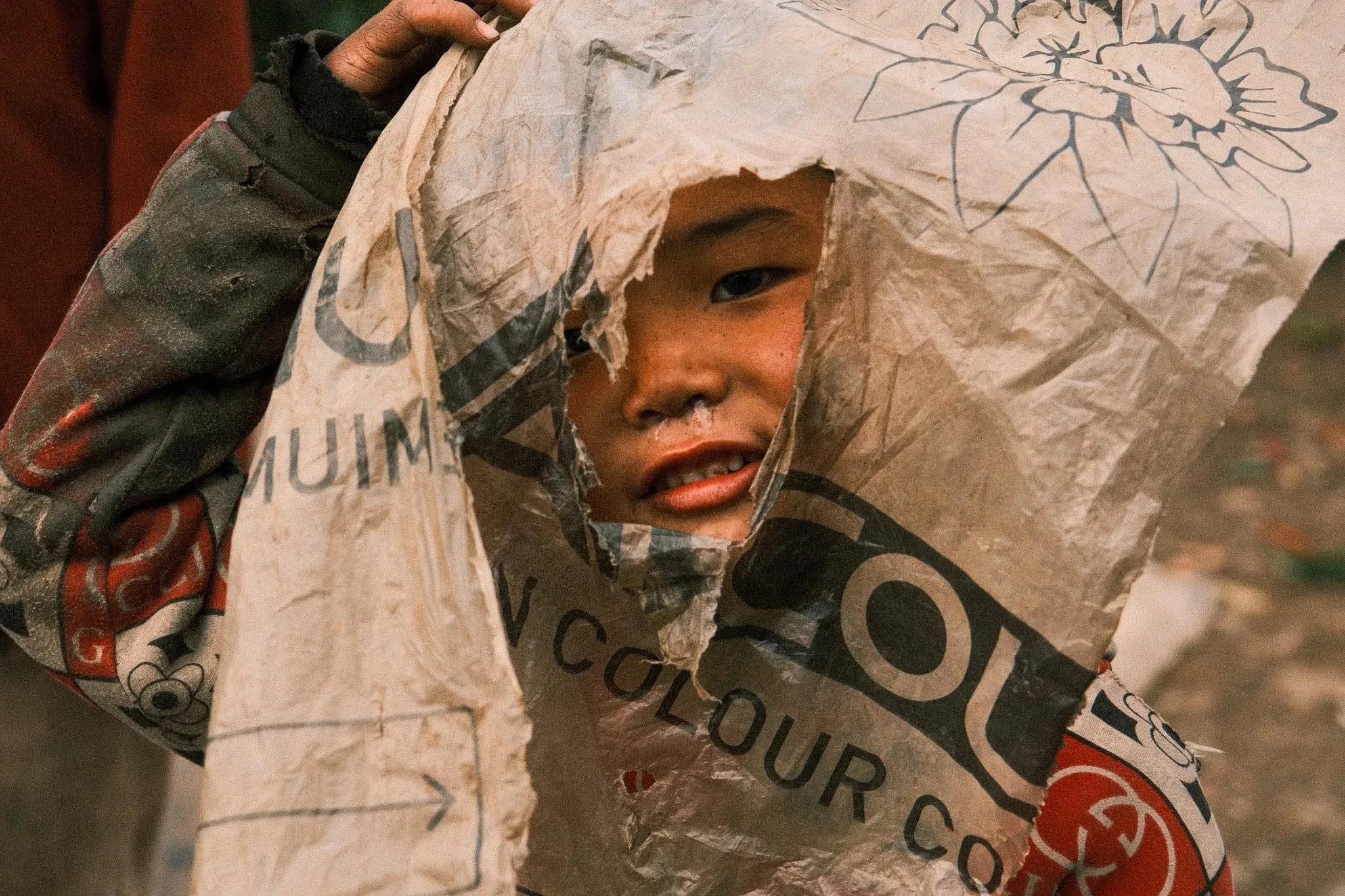 A child peeking out from under a plastic sack worn over the head