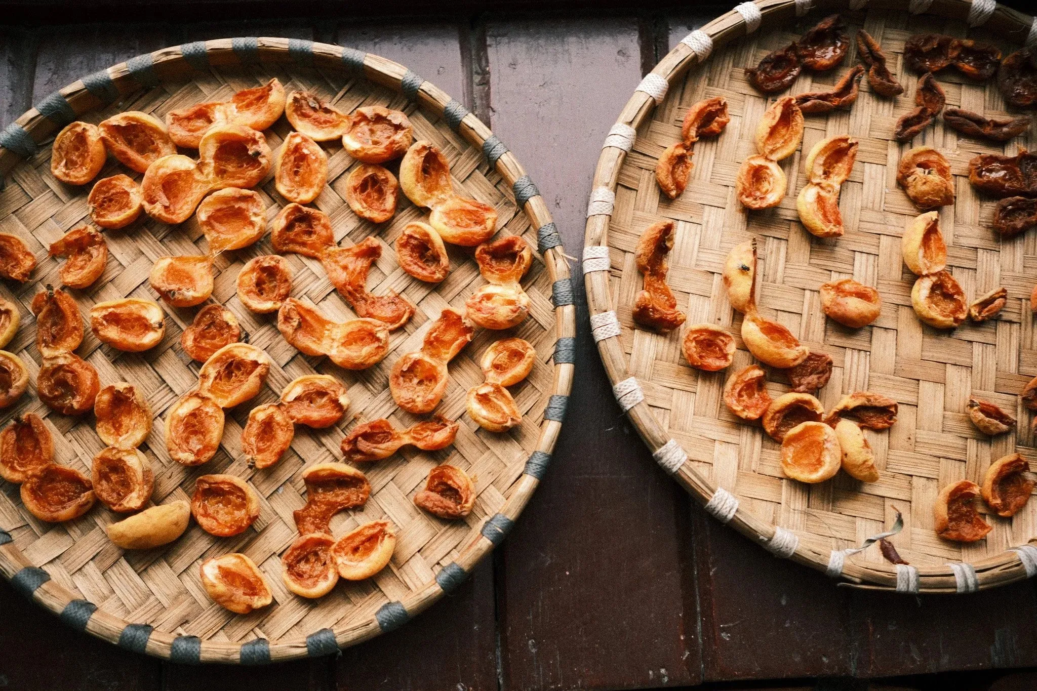 Apricot halves drying on two round woven trays in Marpha