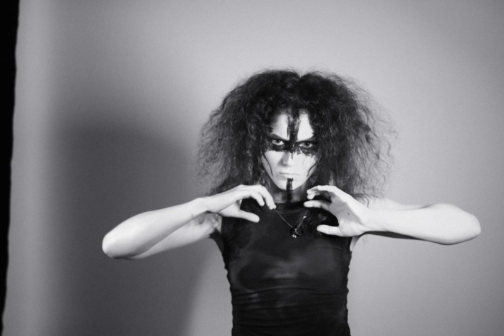 Black and white photo of a model in face paint with hands curled in front of her