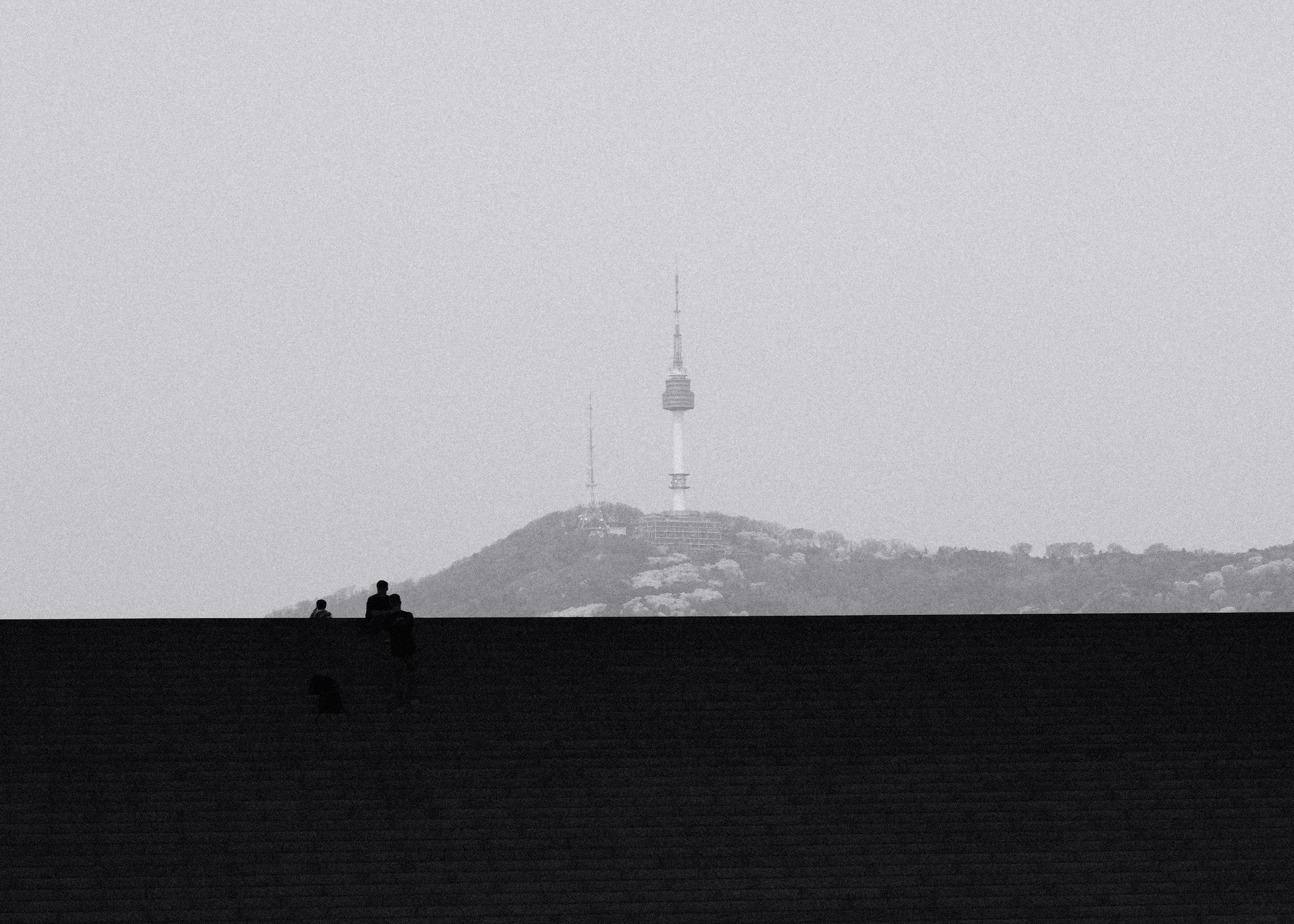 Two people on the steps of the National Museum of Korea, with Namsan Tower on the hill behind