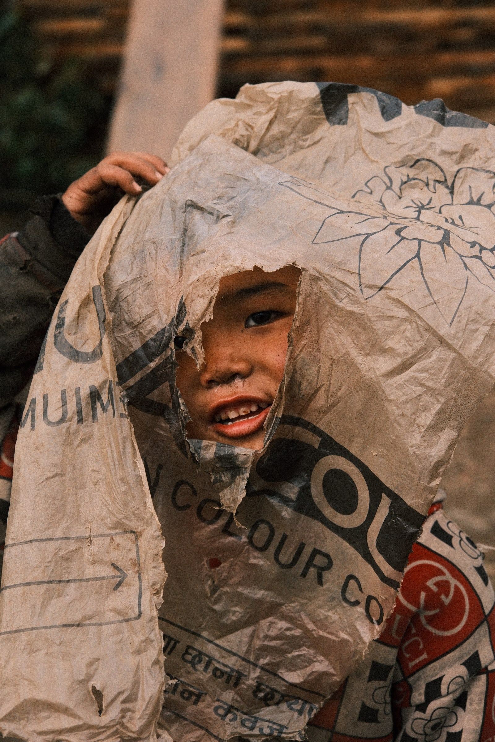 Child peering out from under a large printed plastic sheet