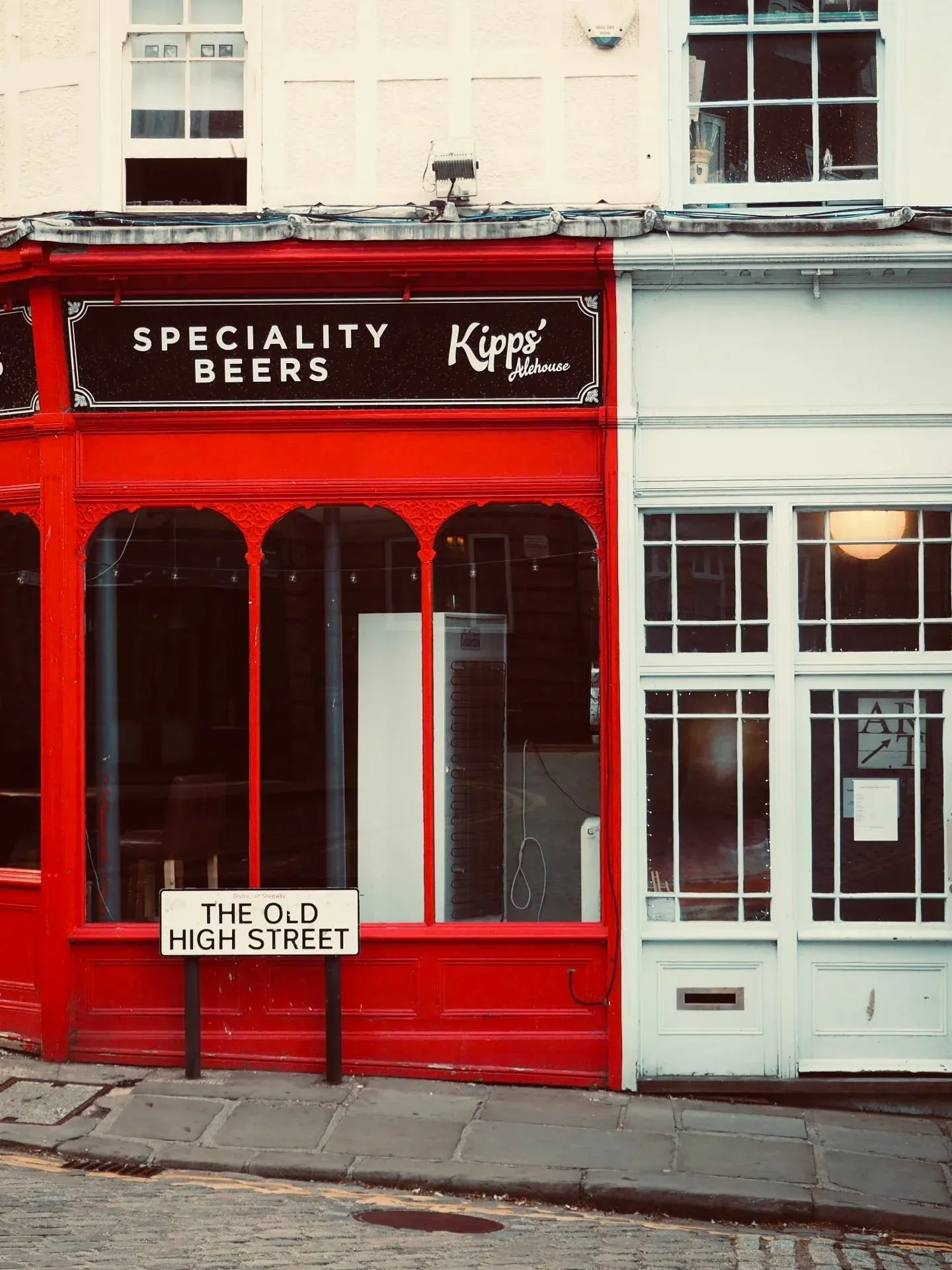 A red shopfront selling speciality beers beside The Old High Street sign