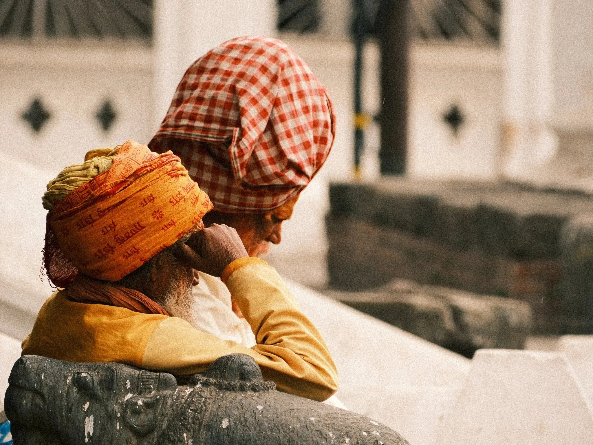 Two sadhus in orange and checked turbans sitting together at Pashupatinath