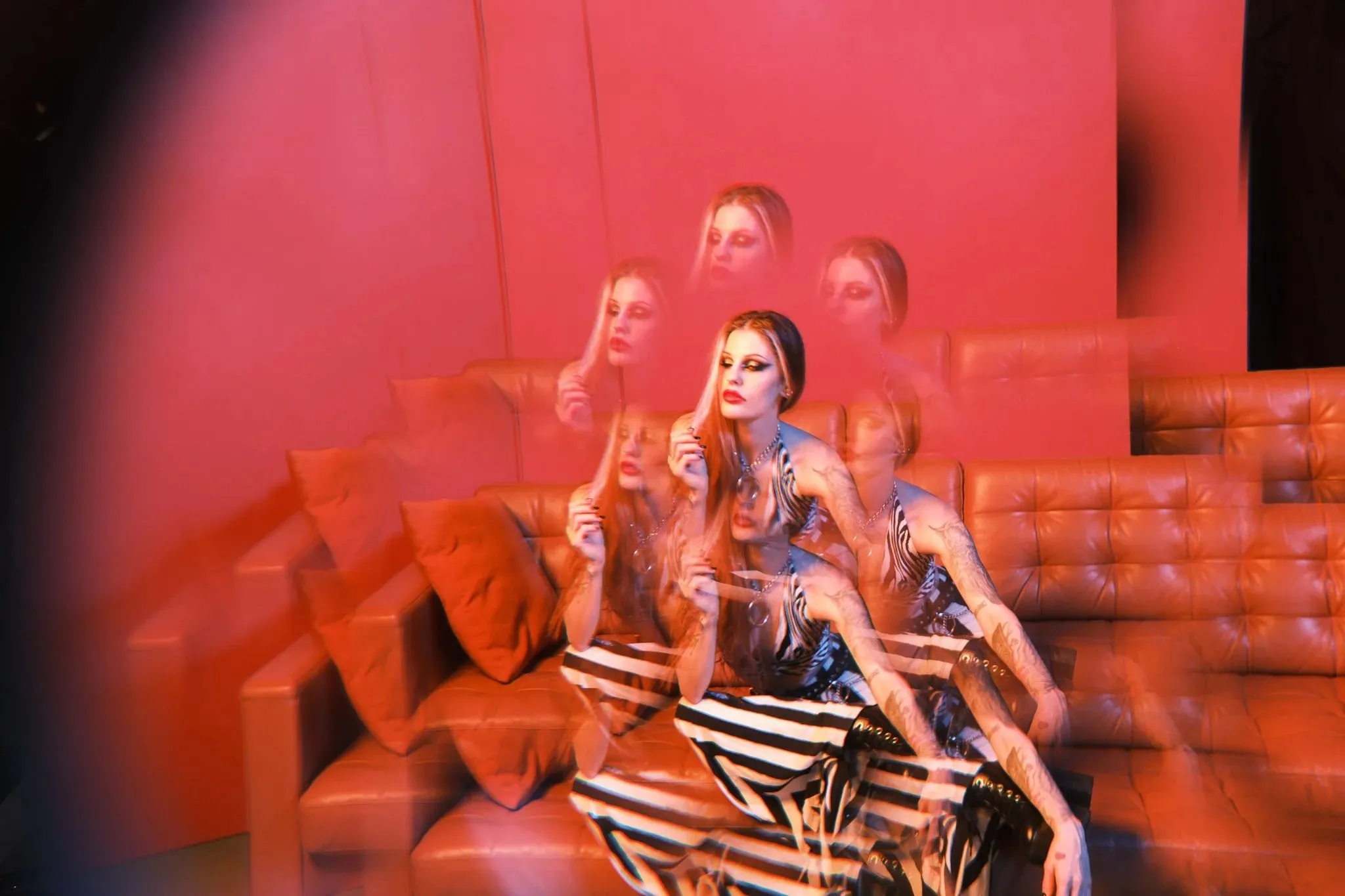 A model on a red sofa repeated several times through a prism effect