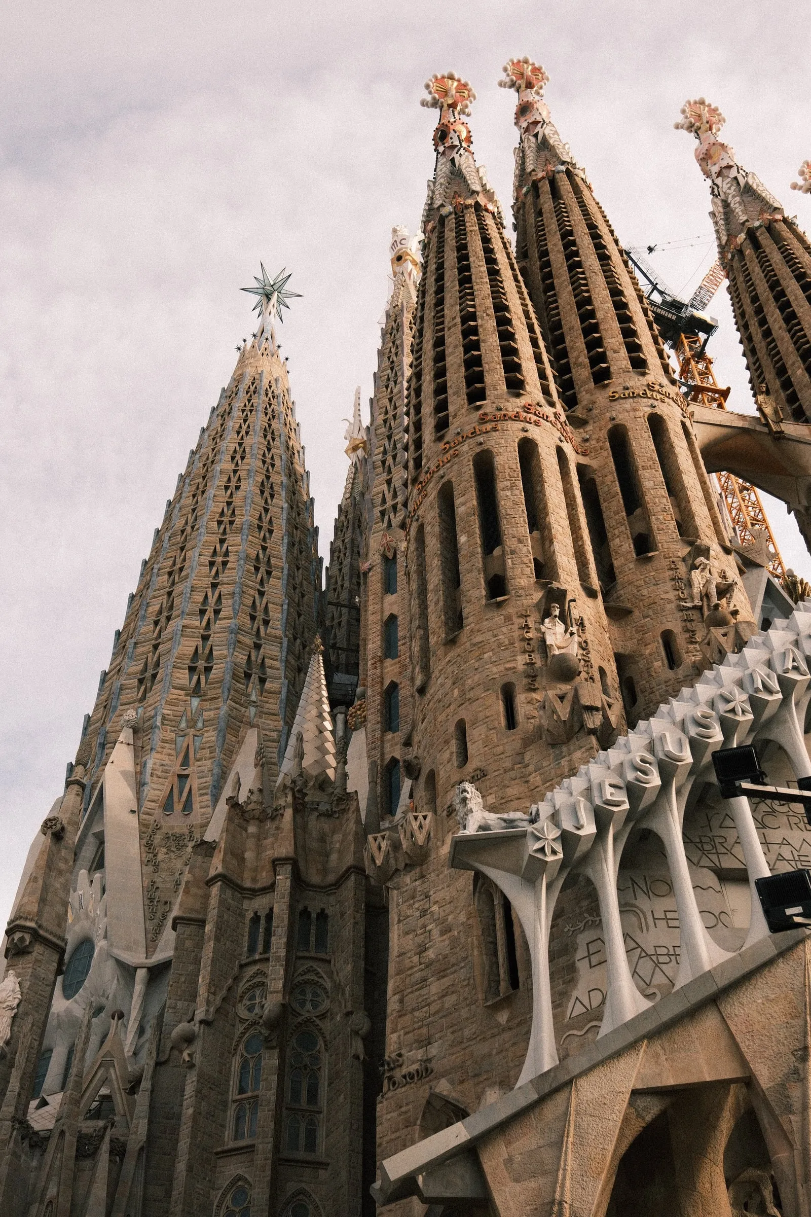 The spires of the Sagrada Família seen from below against a pale sky