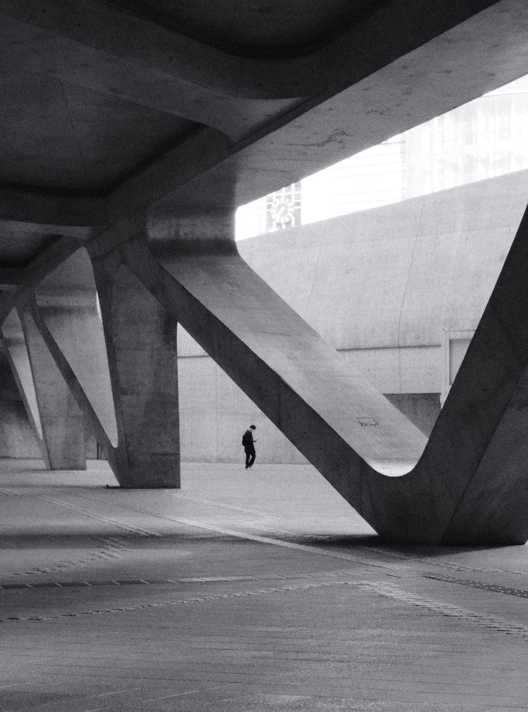 Lone person walking beneath angled concrete supports