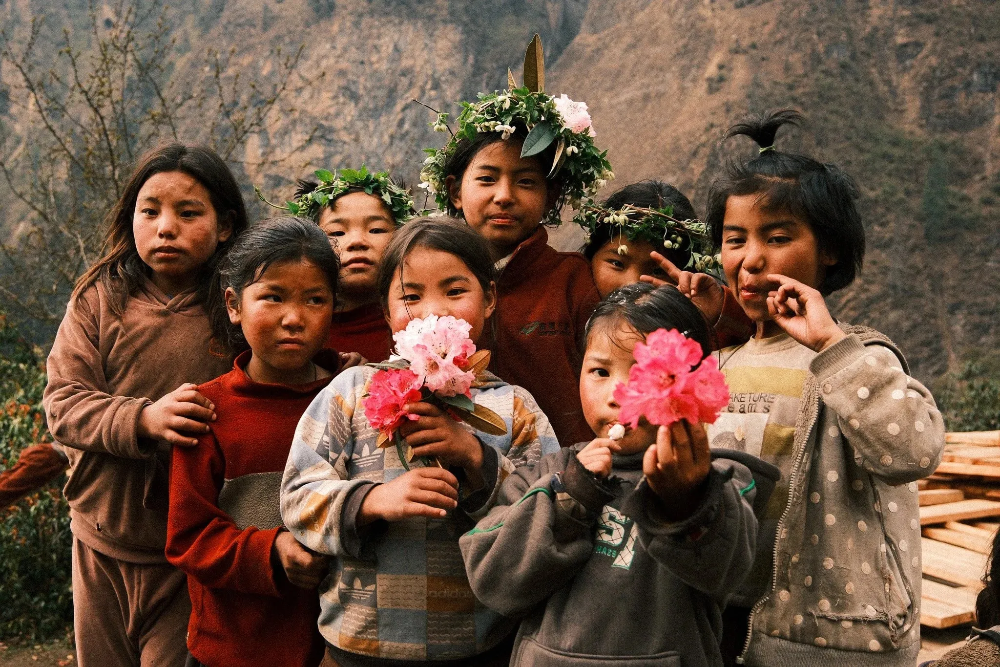 A group of children with flower garlands, some holding pink flowers, on the way to Serang