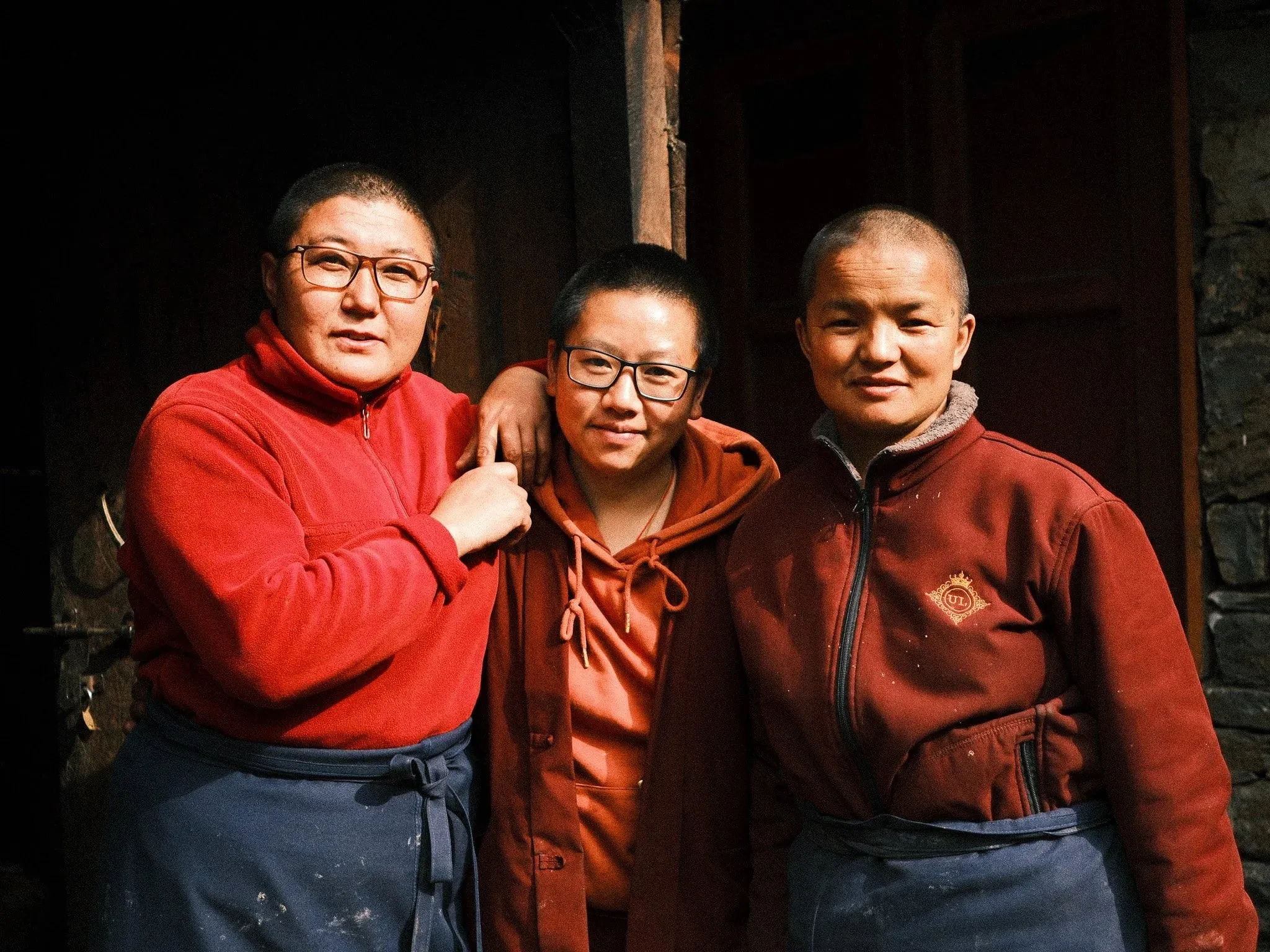 Three nuns in red fleeces standing together in a doorway