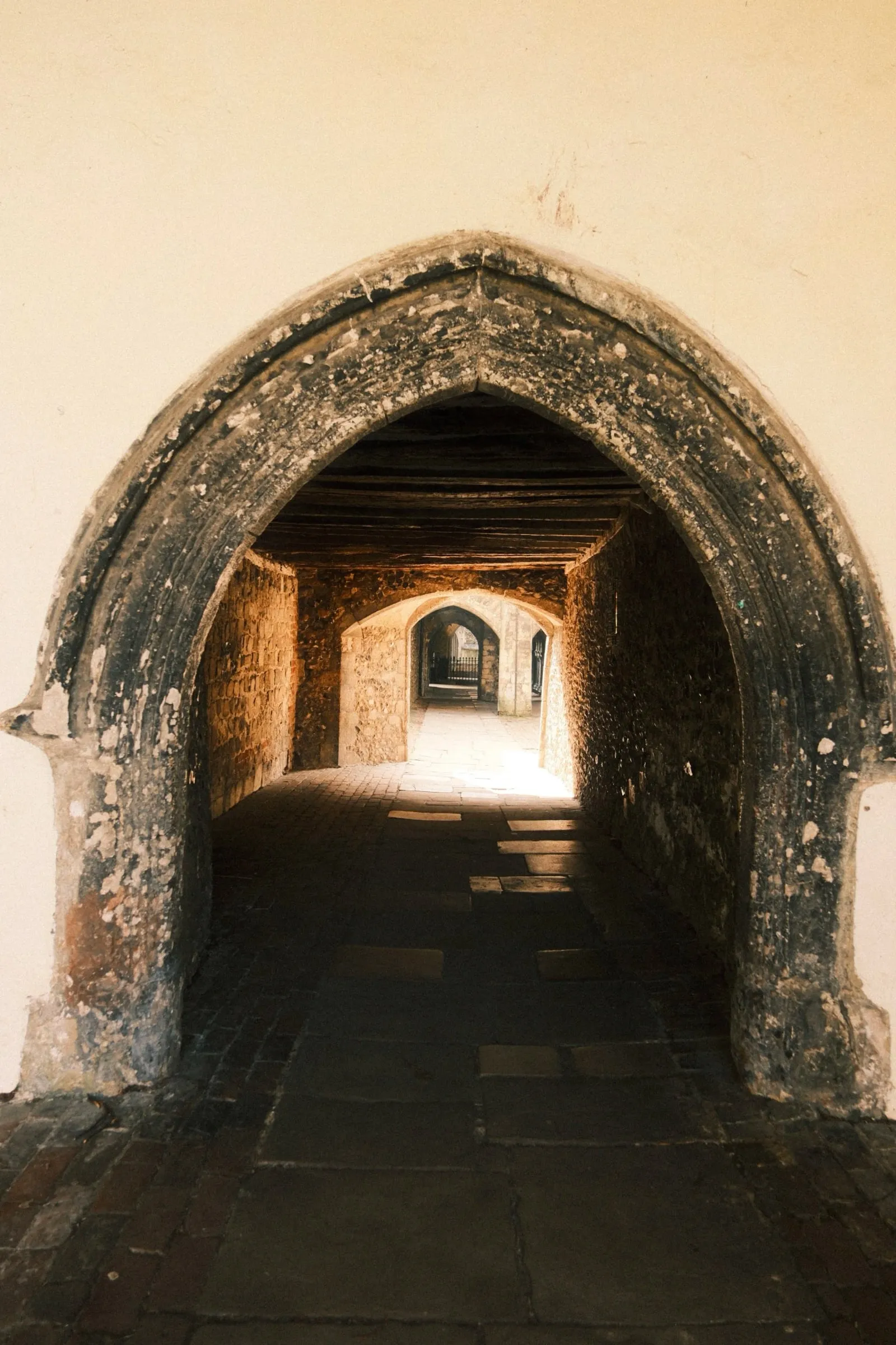 A worn stone archway opening onto a passage with light at the far end