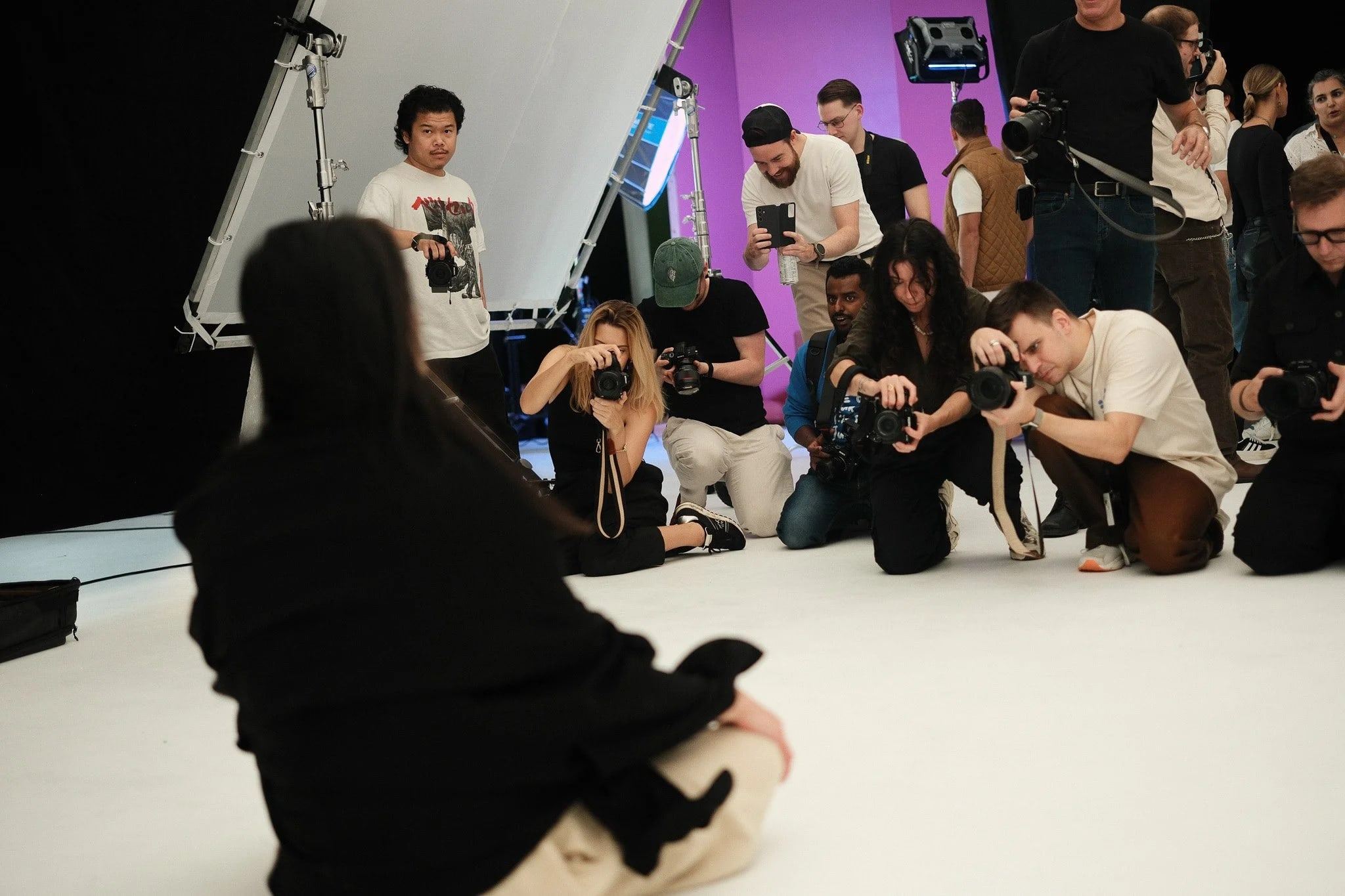 Photographers crouching with cameras around a model in a studio