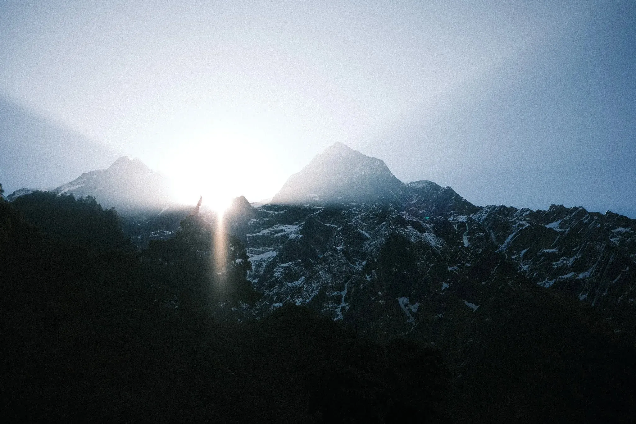 The sun rising behind dark mountain peaks
