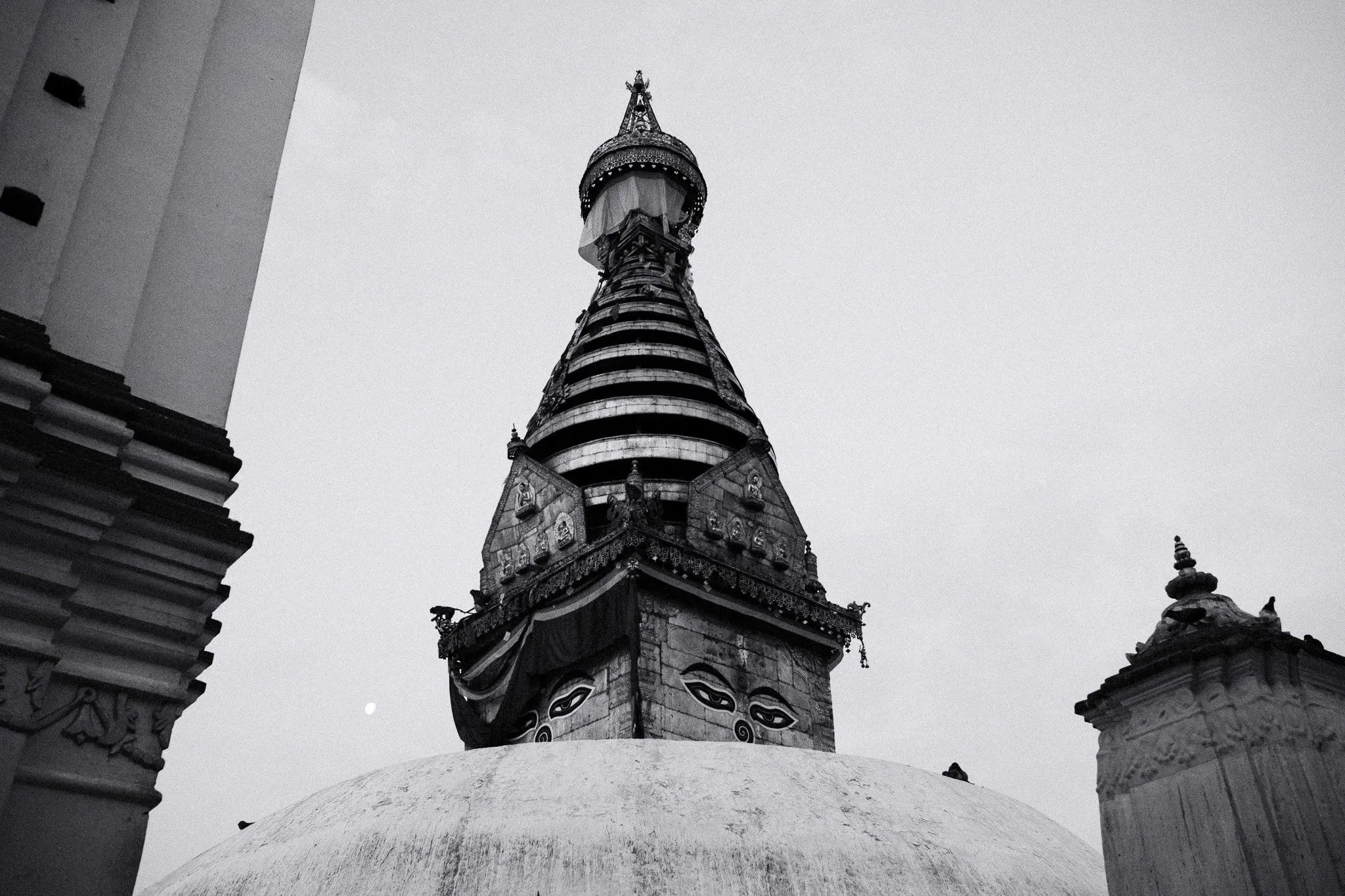 Black and white photo of the painted eyes and spire of the stupa at Swayambhu