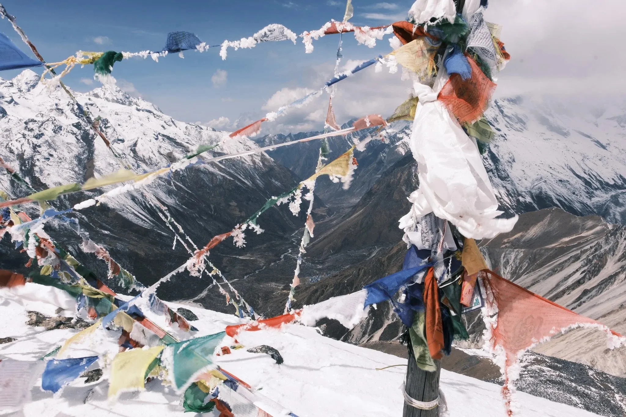 Prayer flags strung across the summit of Tserko Ri with snowy mountains behind