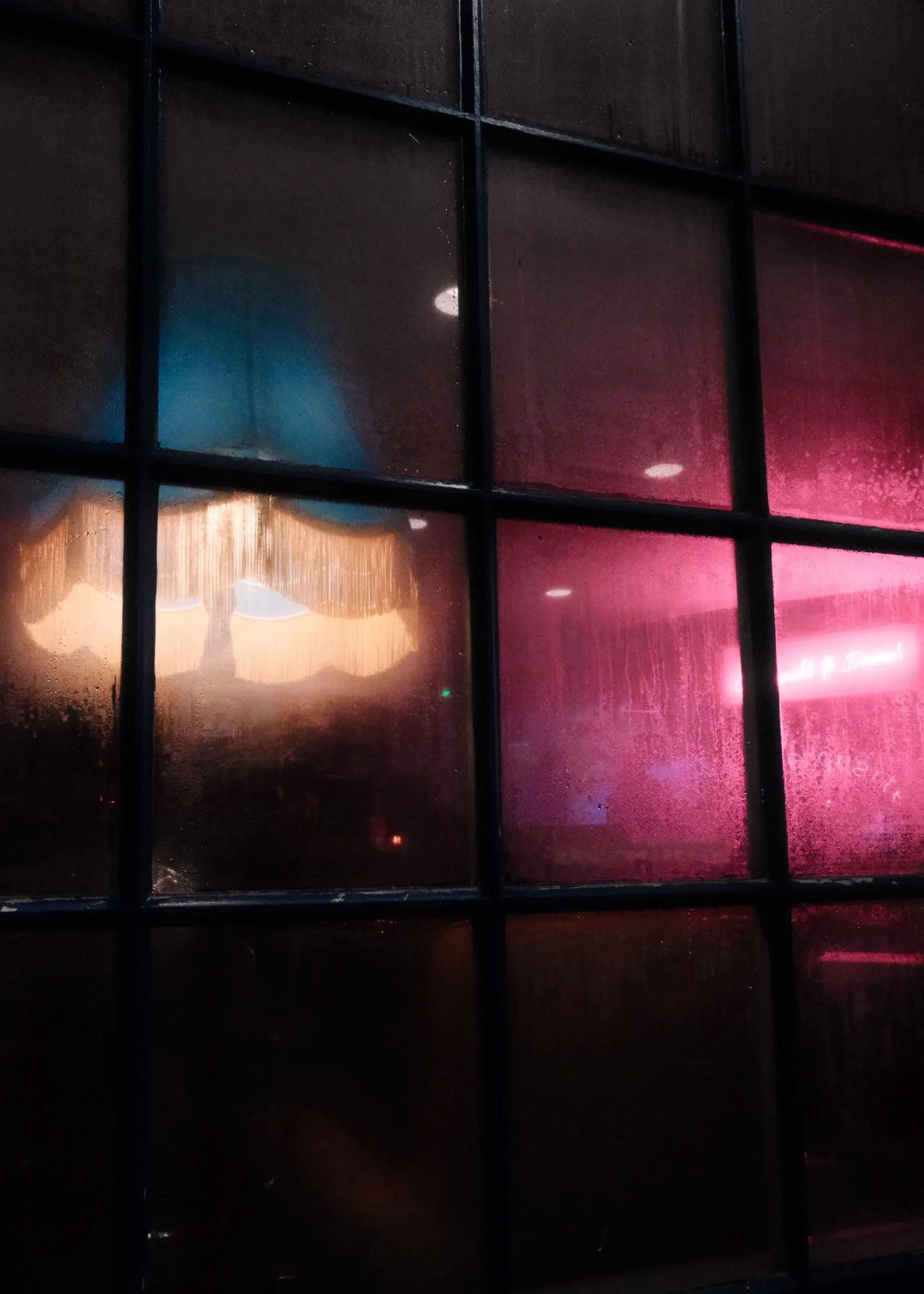 Pink and blue lights glowing through a misted window